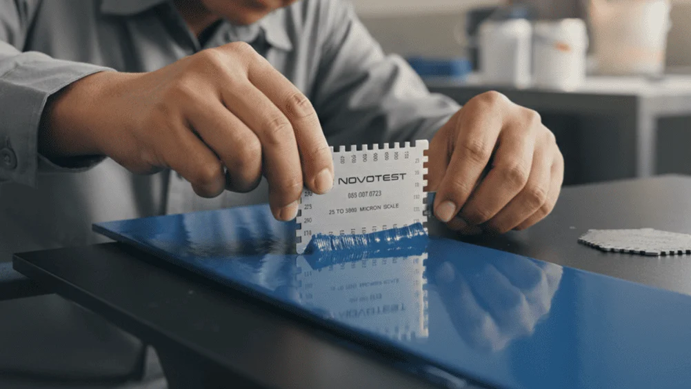 Wet Film Combs NOVOTEST - Kombi pengukur ketebalan film basah dengan jarak gigi berbeda, di atas permukaan cat.