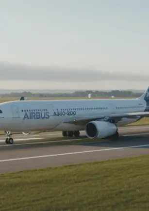 Insiden penerbangan memeriksa bilah turbin mesin pesawat dengan alat uji ultrasonik di hanggar, mencerminkan peran NDT dalam keselamatan penerbangan.